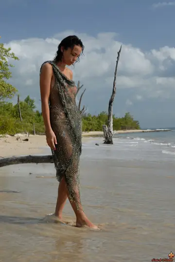 European Woman Poses Nude in Fishnet Dress on the Beach