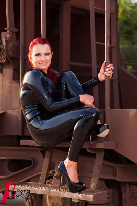 Lara Larsen: Redhead in a Latex Bodysuit and High Heels Poses on a Train Platform – photo 4 of 12