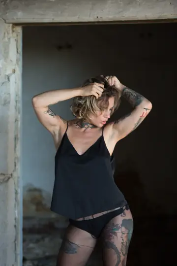 Short-Haired Busty Woman Poses in Pantyhose Showing Her Tattoo