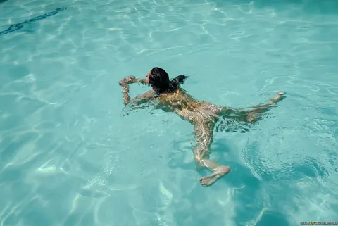 Sidney Alexis: Tall Brunette Slicks Her Big Natural Tits and Ass with Oil Poolside – photo 14 of 21