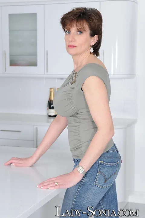 Lady Sonia: Mature British Blonde with Big Tits Poses in Jeans and Heels in the Kitchen – photo 4 of 16