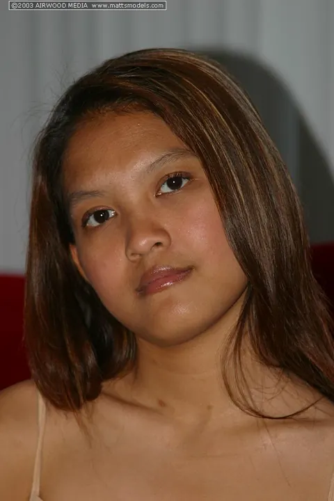 Tai Angel: Asian Brunette Strips Out of Her Jeans on a Red Sofa – photo 1 of 16