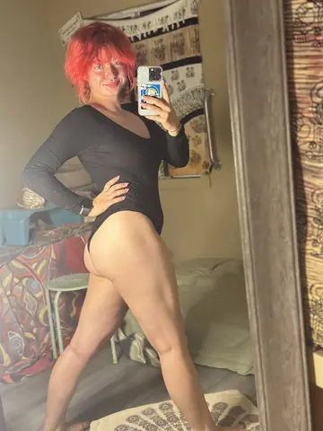 Skinny Redhead Bends Over in Front of a Mirror for a Phone Selfie