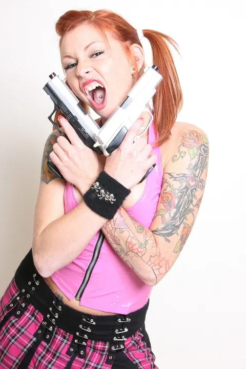 Scarlett Pain: Redhead in a Latex Skirt and Socks Poses with Two Guns – photo 6 of 21