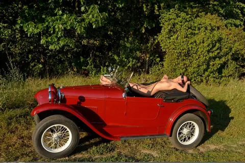 Busty Curly Woman in Glasses Strips Nude Outdoors by a Car – photo 15 of 21