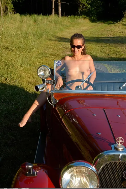 Busty Curly Woman in Glasses Strips Nude Outdoors by a Car – photo 11 of 21