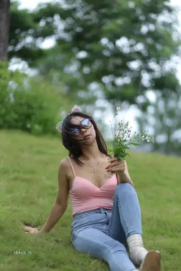 Asian Woman in Glasses Poses in a Skirt Over Jeans Outdoors