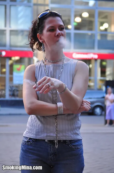 Brunette in Jeans and Glasses Smokes a Cigarette on a Busy Street – photo 13 of 15
