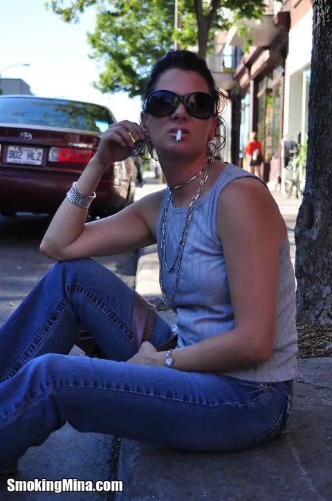 Brunette in Jeans and Glasses Smokes a Cigarette on a Busy Street – photo 6 of 15
