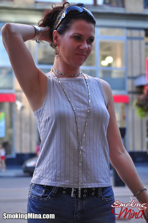Brunette in Jeans and Glasses Smokes a Cigarette on a Busy Street – photo 12 of 15