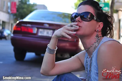 Brunette in Jeans and Glasses Smokes a Cigarette on a Busy Street – photo 5 of 15