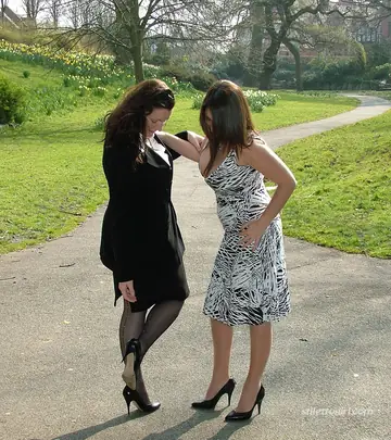 Two Women in Skirts, Stockings and Heels Kiss Outdoors