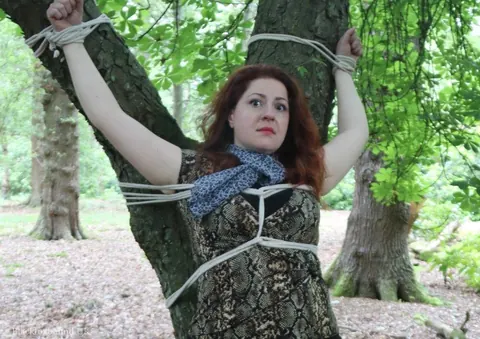 Redhead Bound to a Tree in a Forest Wearing a Skirt – photo 10 of 16