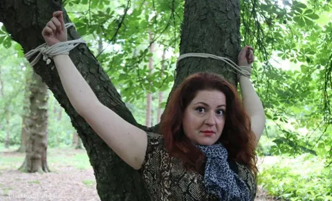 Redhead Bound to a Tree in a Forest Wearing a Skirt – photo 15 of 16