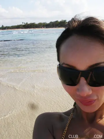Mature Asian Woman Poses in a Bikini and Shorts on the Beach