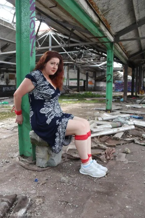 Curvy Redhead Bound and Gagged to a Post in a Warehouse – photo 3 of 16