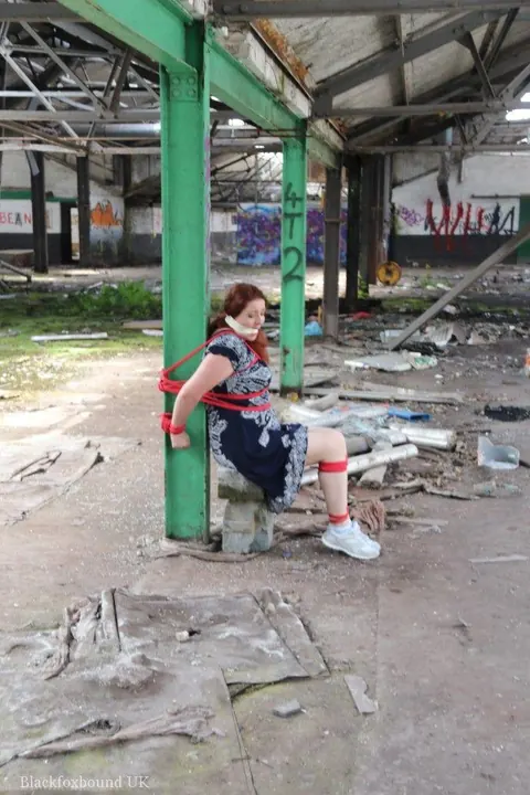 Curvy Redhead Bound and Gagged to a Post in a Warehouse – photo 15 of 16