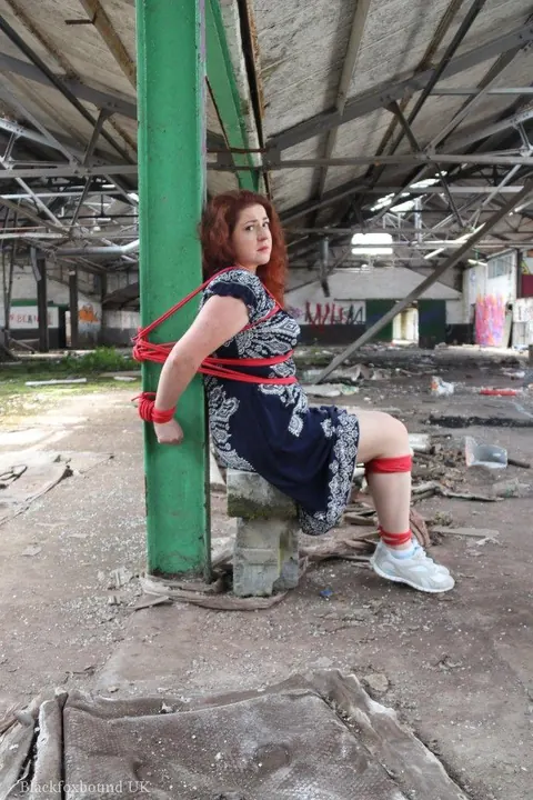 Curvy Redhead Bound and Gagged to a Post in a Warehouse – photo 8 of 16