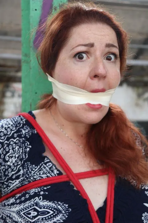 Curvy Redhead Bound and Gagged to a Post in a Warehouse – photo 11 of 16