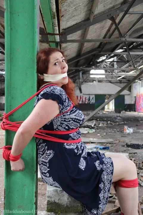 Curvy Redhead Bound and Gagged to a Post in a Warehouse – photo 13 of 16