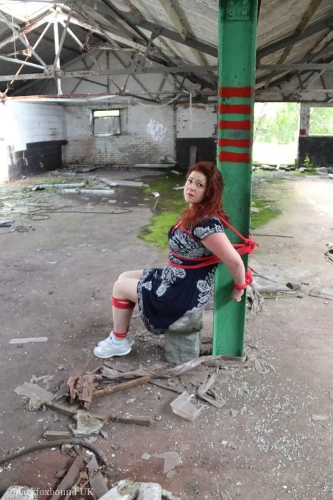 Curvy Redhead Bound and Gagged to a Post in a Warehouse – photo 9 of 16