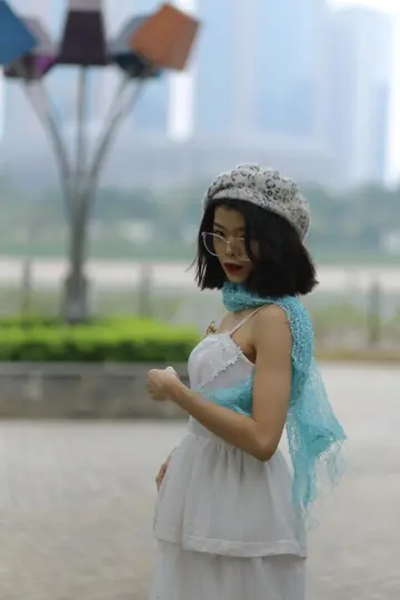 Asian Brunette Poses in a White Dress and Hat Outdoors