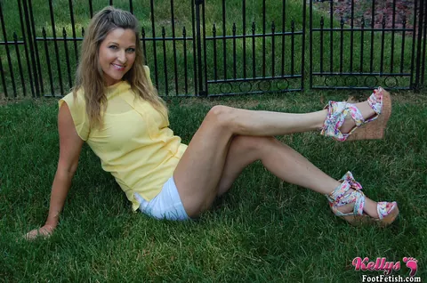 Kelly Anderson: Brunette MILF in Shorts and High Heels Shows Her Feet on Lush Grass – photo 3 of 15