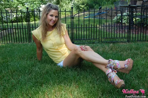 Kelly Anderson: Brunette MILF in Shorts and High Heels Shows Her Feet on Lush Grass – photo 7 of 15