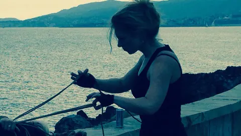 Blonde Hangs Suspended in Rope Bondage Outdoors Fully Clothed – photo 3 of 16