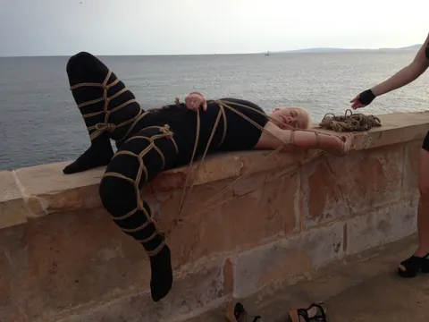 Blonde Hangs Suspended in Rope Bondage Outdoors Fully Clothed – photo 7 of 16