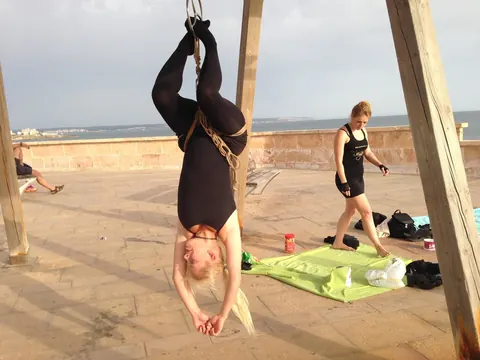 Blonde Hangs Suspended in Rope Bondage Outdoors Fully Clothed – photo 11 of 16