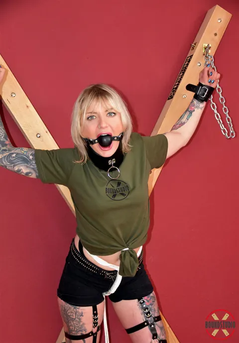 Blonde in Shorts and Socks Chained to a Cross in Bondage – photo 11 of 16
