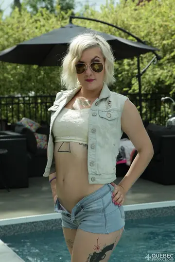 Short-Haired Blonde in a Bikini and Glasses Strips by the Pool