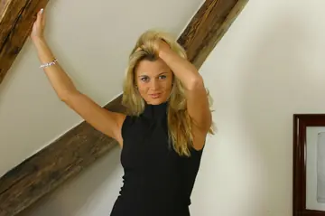 Blonde in a Dress and Pantyhose Pulls Skirt Aside on the Bed